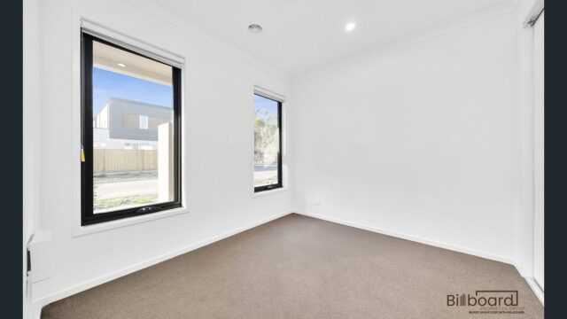 Bright empty bedroom with carpet flooring, white walls and large windows in a contemporary Melbourne home.