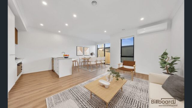 Modern furnished open plan living and dining area with timber flooring, white kitchen island, and contemporary interior styling in a Melbourne home.