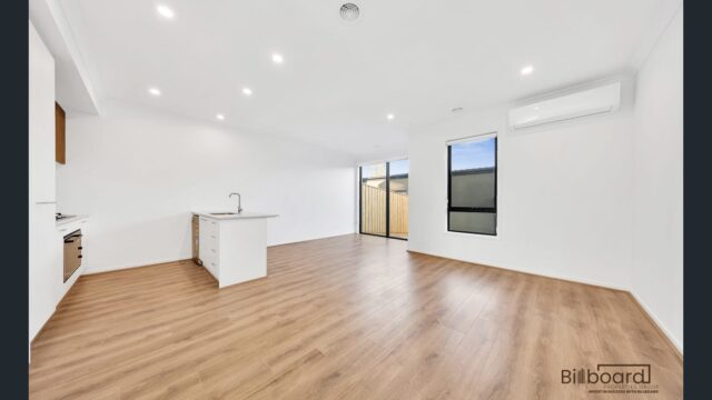 Spacious open living area with timber flooring, split system air conditioning, and modern white kitchen in a contemporary Melbourne home.