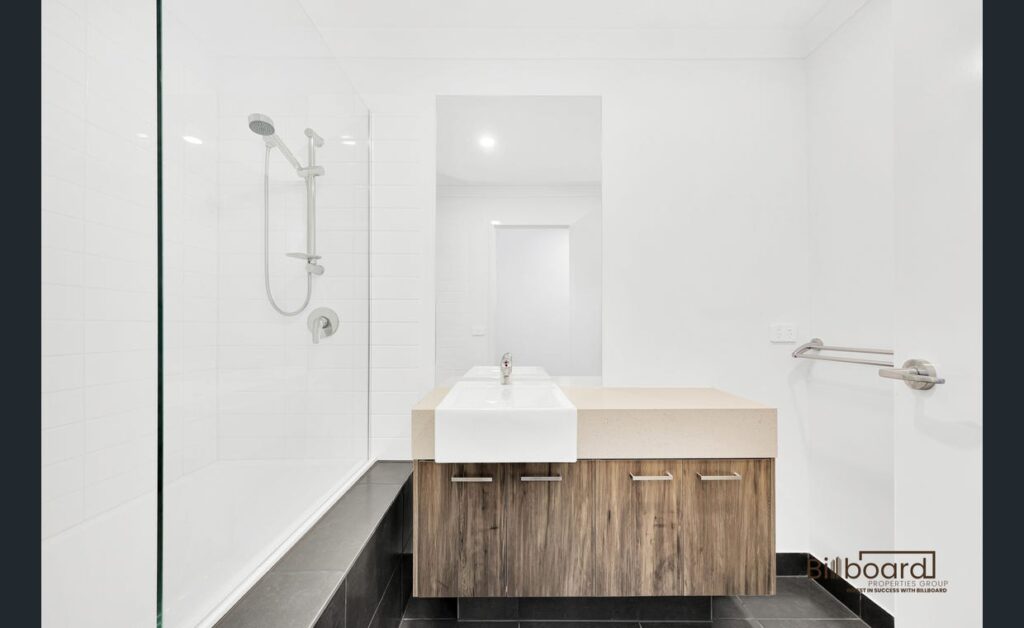 Modern white bathroom with walk-in shower, wooden vanity cabinet and minimalist interior design in a Melbourne home.
