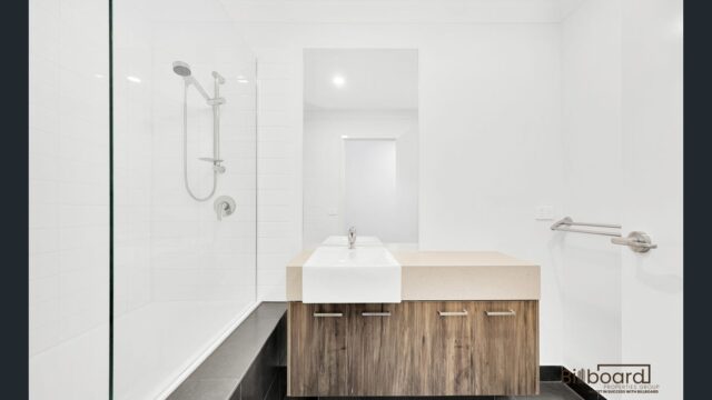 Modern white bathroom with walk-in shower, wooden vanity cabinet and minimalist interior design in a Melbourne home.