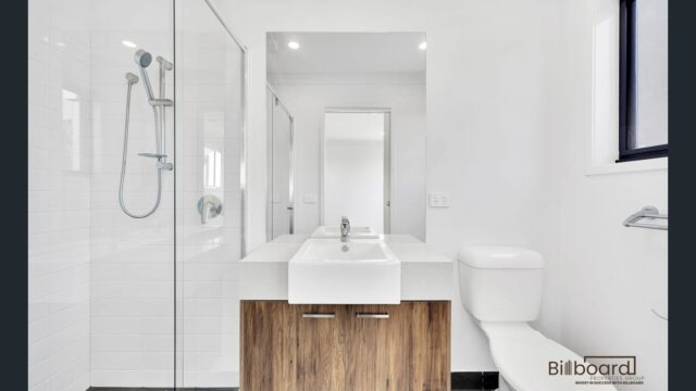 Modern bathroom with glass shower, wooden vanity cabinet and white basin in a contemporary Melbourne property.
