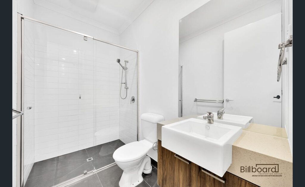 Compact modern bathroom with glass shower, wall mounted vanity and contemporary white interior in a Melbourne home.