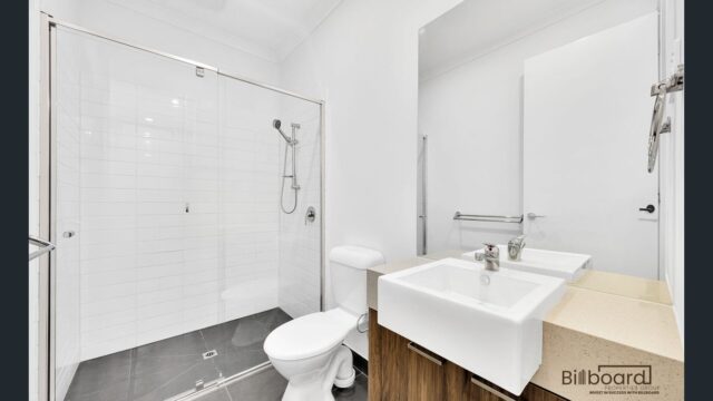 Compact modern bathroom with glass shower, wall mounted vanity and contemporary white interior in a Melbourne home.