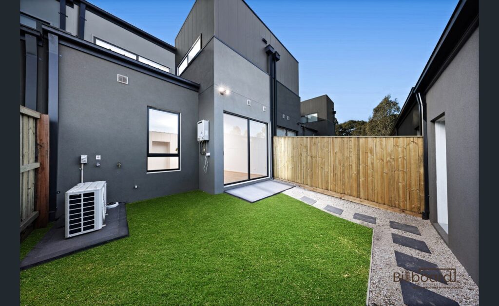 Low-maintenance backyard with synthetic lawn, paved pathway and modern exterior design at a contemporary home in Wollert.