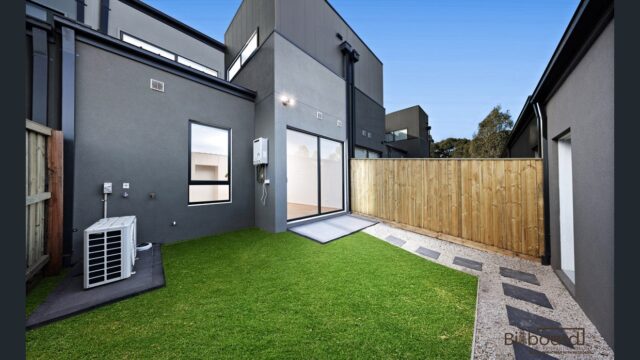 Low-maintenance backyard with synthetic lawn, paved pathway and modern exterior design at a contemporary home in Wollert.