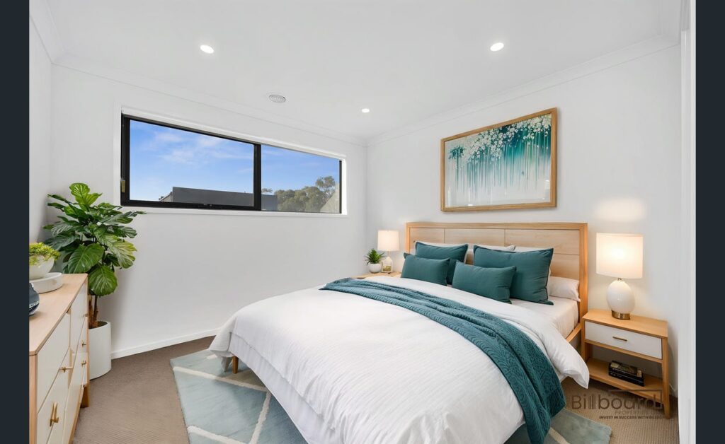 Beautifully furnished bedroom with wooden bed frame, teal accent decor, bedside lamps and large window providing natural light in a modern Melbourne home.