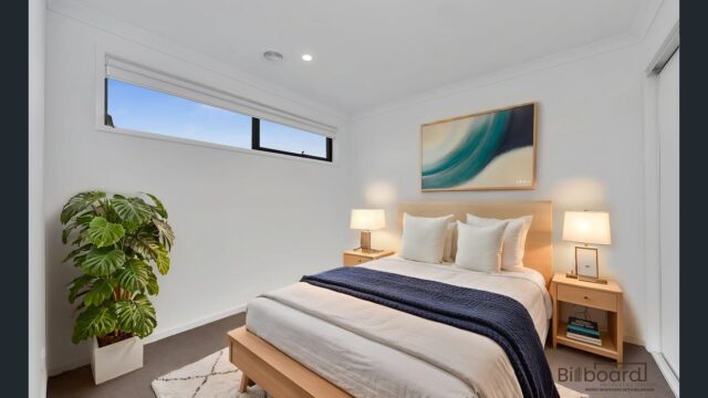 Modern furnished bedroom with wooden bed frame, bedside lamps, indoor plant and soft neutral styling in a contemporary Melbourne home.