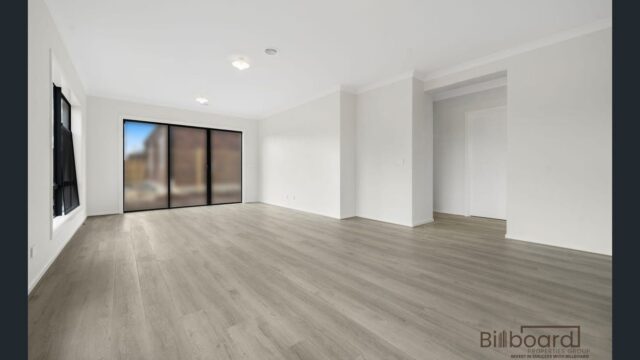 Large open living area with timber flooring, white walls and sliding glass doors in a modern Melbourne home.
