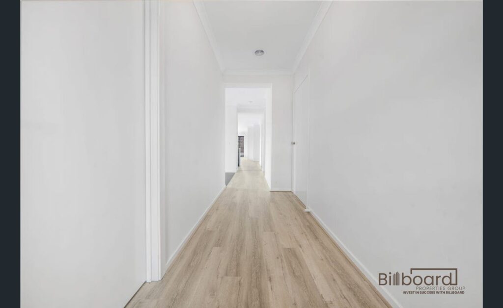 Bright and long hallway with white walls, light timber flooring, and minimal modern interior design leading towards multiple rooms at the end of the corridor.