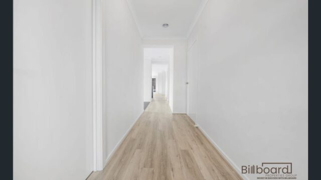Bright and long hallway with white walls, light timber flooring, and minimal modern interior design leading towards multiple rooms at the end of the corridor.
