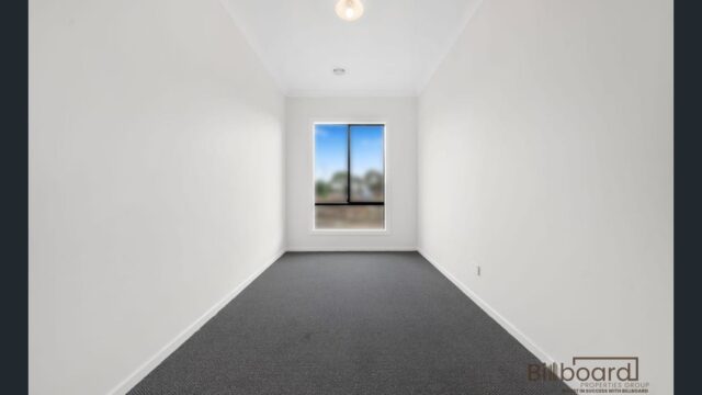 Empty narrow room with carpet flooring, white walls and a single window providing natural light in a modern Melbourne home.