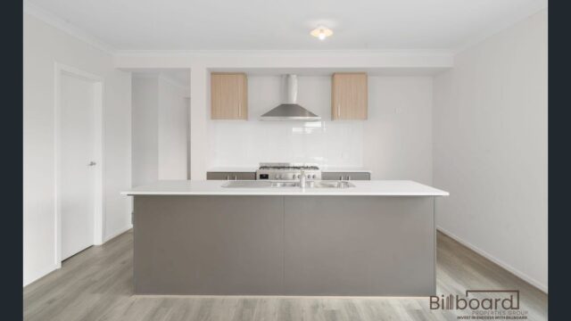 Modern kitchen with central island bench, stainless steel appliances, rangehood and timber flooring in a contemporary Melbourne home.