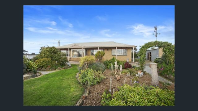 Farmhouse with well-maintained garden, green lawn and landscaped plants set in open rural countryside.