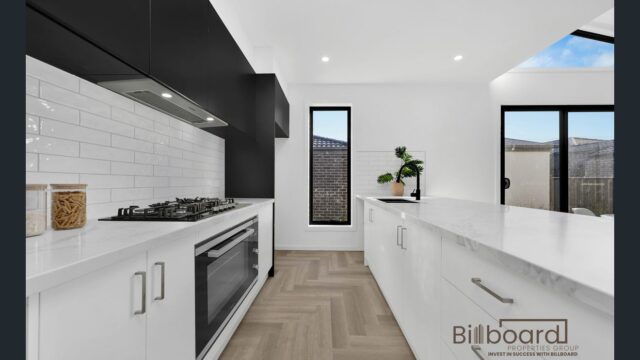Modern white kitchen with marble countertops, herringbone flooring, gas cooktop and sleek cabinetry in a contemporary Melbourne home.