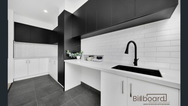 Contemporary kitchen featuring black upper cabinets and white lower cabinets with a sink and countertop.