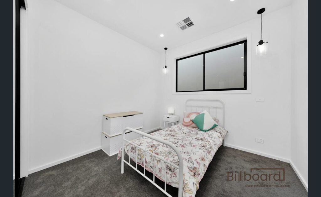 Minimalist single bedroom with white bed frame, pendant lighting and clean modern interiors in a Melbourne home.