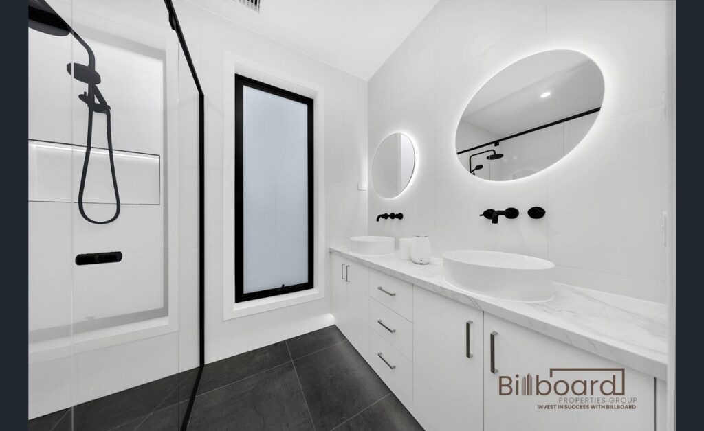 Contemporary bathroom with walk-in shower, double vanity, circular LED mirrors and sleek minimalist white interior in a Melbourne home.