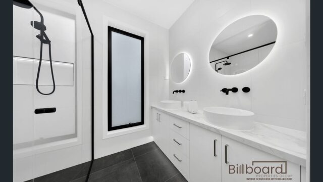 Contemporary bathroom with walk-in shower, double vanity, circular LED mirrors and sleek minimalist white interior in a Melbourne home.
