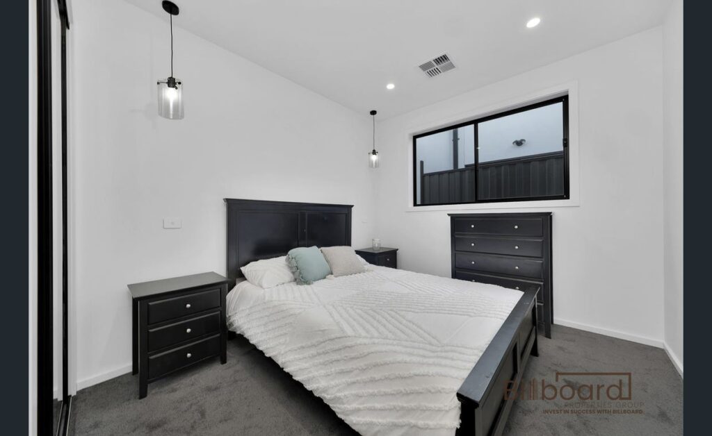 Minimalist modern bedroom with dark timber bed frame, matching side tables, soft pendant lighting and neutral decor in a contemporary Melbourne home.