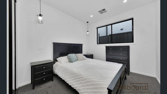 Minimalist modern bedroom with dark timber bed frame, matching side tables, soft pendant lighting and neutral decor in a contemporary Melbourne home.