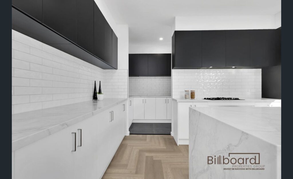 Stylish modern kitchen with white countertops, black upper cabinets, herringbone timber flooring and sleek minimalist design in a Melbourne home.