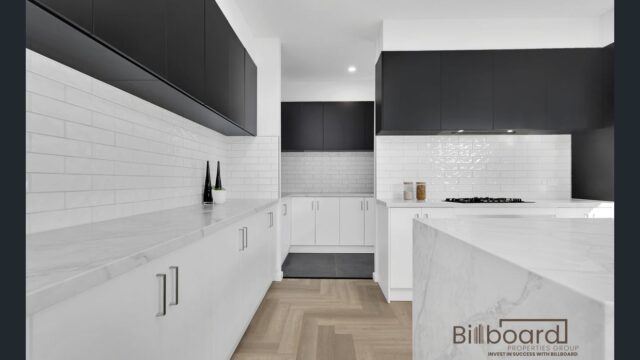 Stylish modern kitchen with white countertops, black upper cabinets, herringbone timber flooring and sleek minimalist design in a Melbourne home.